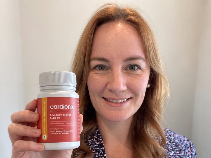Mujer sosteniendo un bote de Cardionix, la toma diaria antes de la comida principal